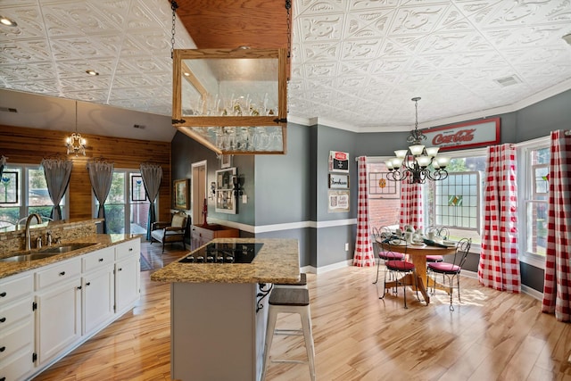 kitchen featuring a kitchen island, black electric cooktop, a kitchen breakfast bar, sink, and white cabinets