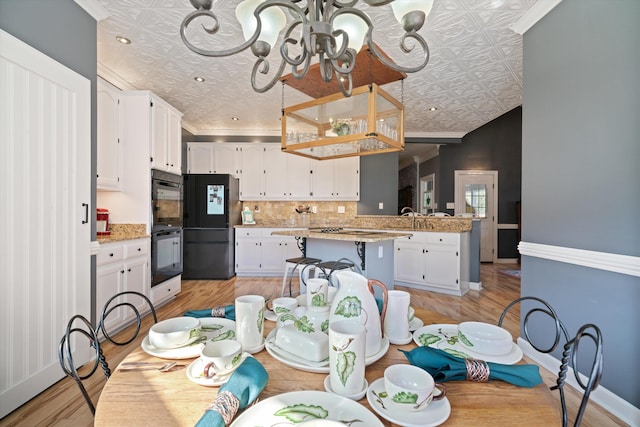 dining area featuring light hardwood / wood-style floors, crown molding, sink, and an inviting chandelier