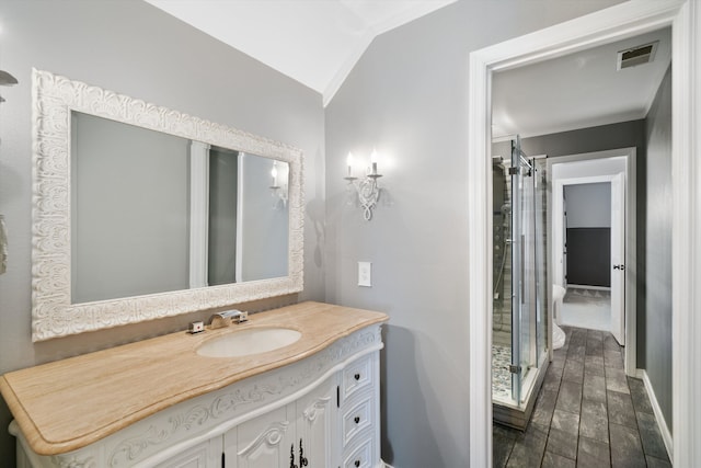 bathroom featuring hardwood / wood-style floors, vaulted ceiling, toilet, vanity, and a shower with curtain