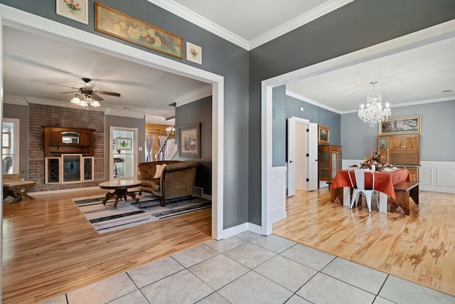 dining space featuring ornamental molding, a brick fireplace, and light wood-type flooring