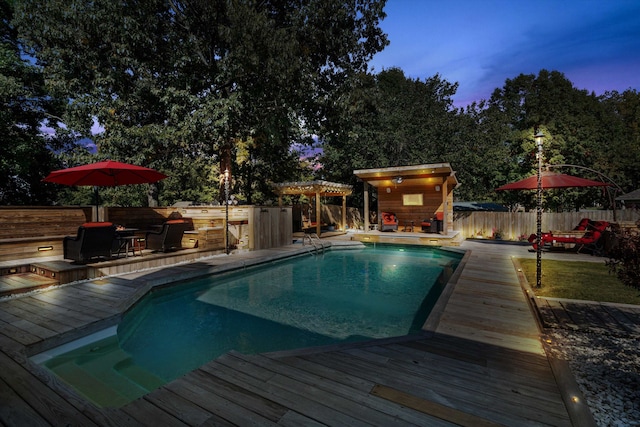 pool at dusk featuring an outdoor bar and a wooden deck