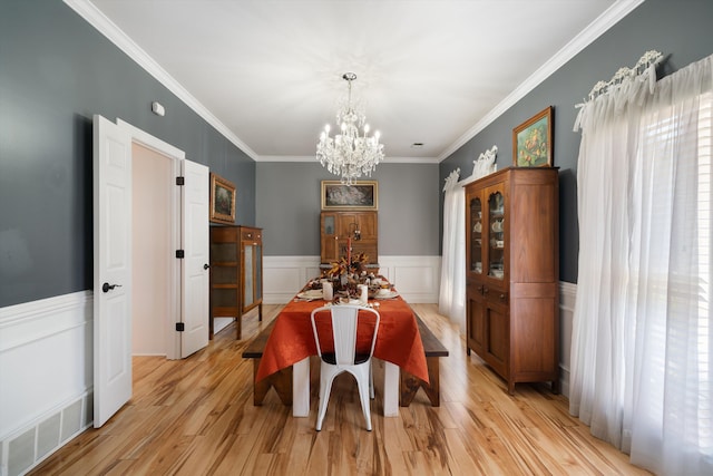 dining room featuring light hardwood / wood-style flooring, ornamental molding, and a chandelier