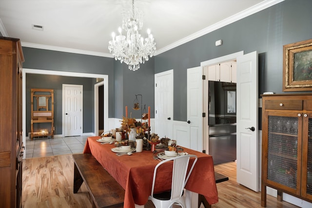 dining room with a notable chandelier, wine cooler, crown molding, and light hardwood / wood-style floors