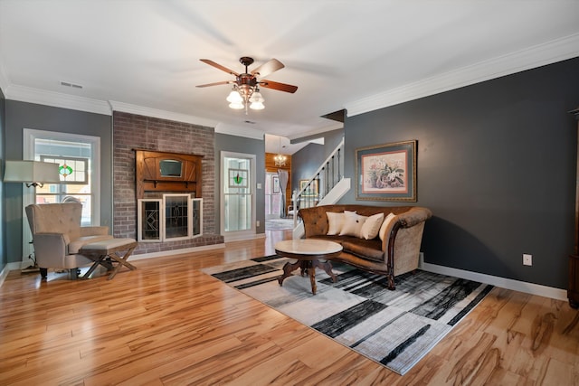 living room featuring light hardwood / wood-style floors, crown molding, a fireplace, and ceiling fan