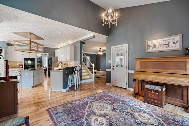 living room featuring light hardwood / wood-style floors, a high ceiling, and ceiling fan with notable chandelier