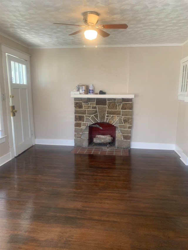 living room featuring a stone fireplace, dark hardwood / wood-style floors, crown molding, a textured ceiling, and ceiling fan