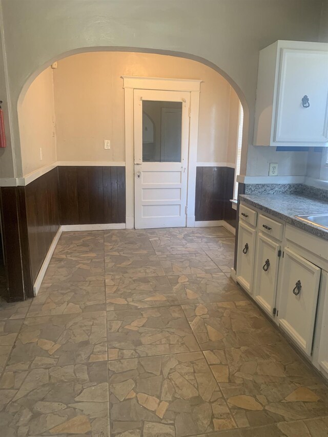 1616 Kendale Ave, Memphis, TN 38106 - interior space featuring stone floors, a wainscoted wall, white cabinets, and arched walkways