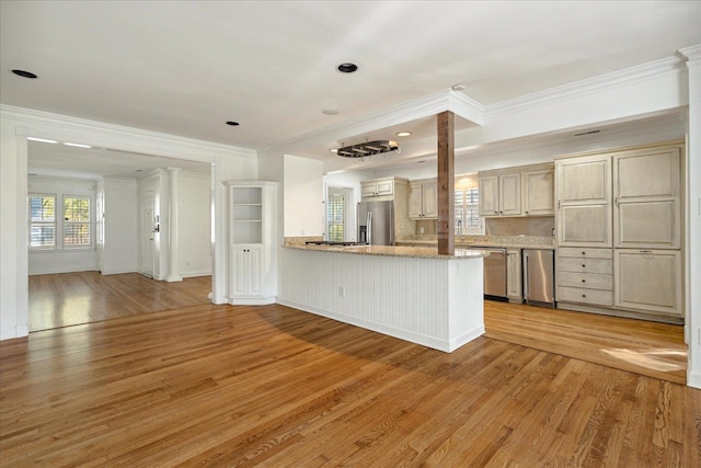 kitchen featuring stainless steel appliances, cream cabinets, light hardwood / wood-style flooring, and ornamental molding