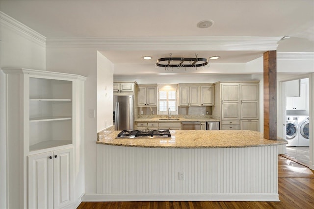 kitchen with hardwood / wood-style flooring, crown molding, sink, appliances with stainless steel finishes, and washing machine and clothes dryer