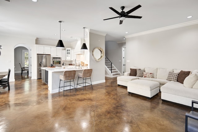 living room with ornamental molding, sink, and ceiling fan