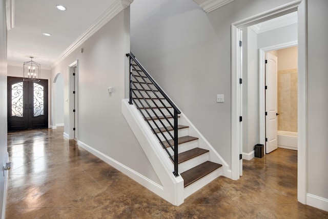 foyer entrance featuring ornamental molding, french doors, and an inviting chandelier