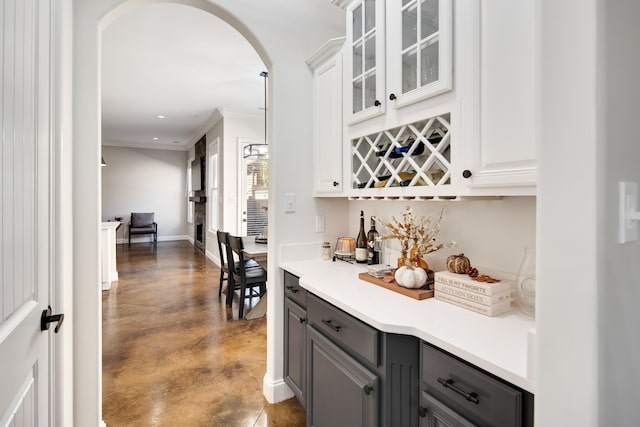 bar with ornamental molding, white cabinets, hanging light fixtures, and gray cabinetry