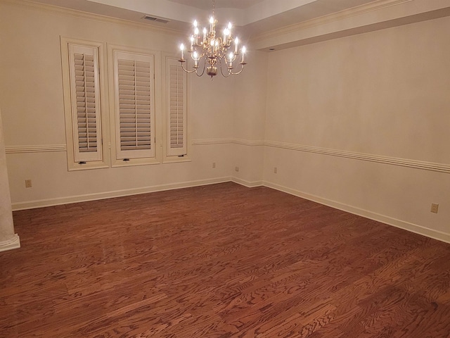 spare room with crown molding, dark hardwood / wood-style floors, and a chandelier