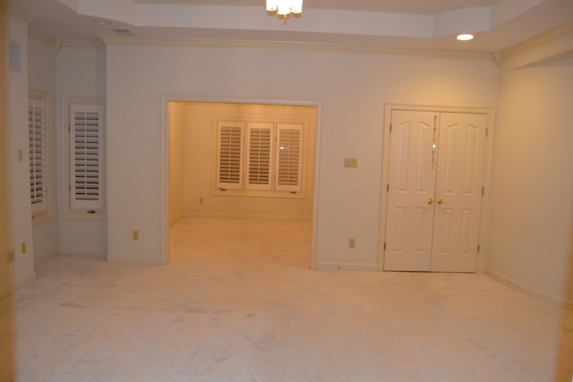 unfurnished bedroom featuring ornamental molding, light colored carpet, and a raised ceiling