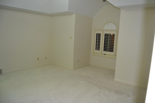 carpeted spare room featuring high vaulted ceiling