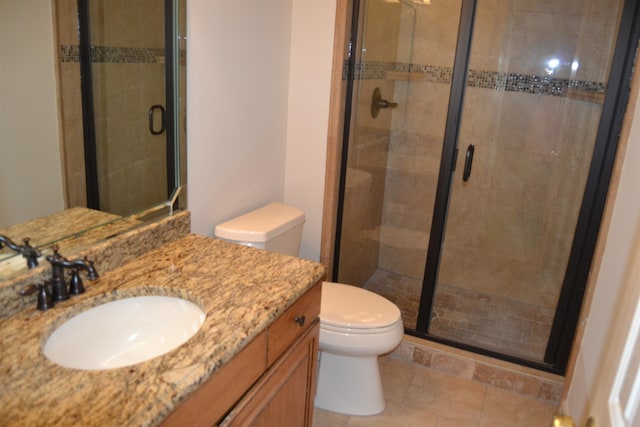 bathroom featuring vanity, toilet, a shower with shower door, and tile patterned flooring