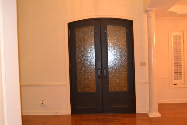 foyer entrance with ornamental molding, french doors, dark hardwood / wood-style floors, and decorative columns