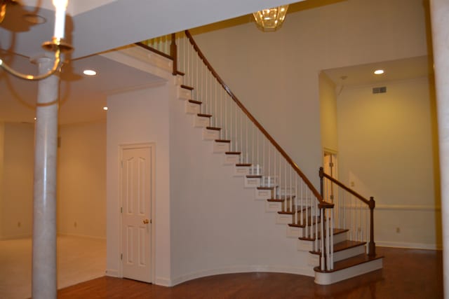 stairs with hardwood / wood-style floors, a notable chandelier, and a towering ceiling