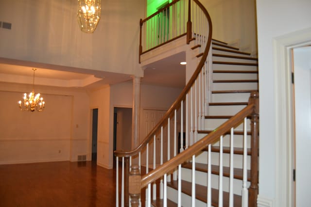 stairs with an inviting chandelier, a high ceiling, and decorative columns