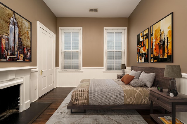376 Mulberry St, Memphis, TN 38103 - bedroom featuring a wainscoted wall, a fireplace with raised hearth, wood finished floors, and visible vents