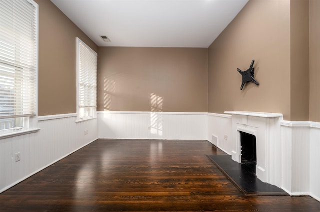 376 Mulberry St, Memphis, TN 38103 - unfurnished living room with a wainscoted wall, a fireplace with raised hearth, wood finished floors, and visible vents