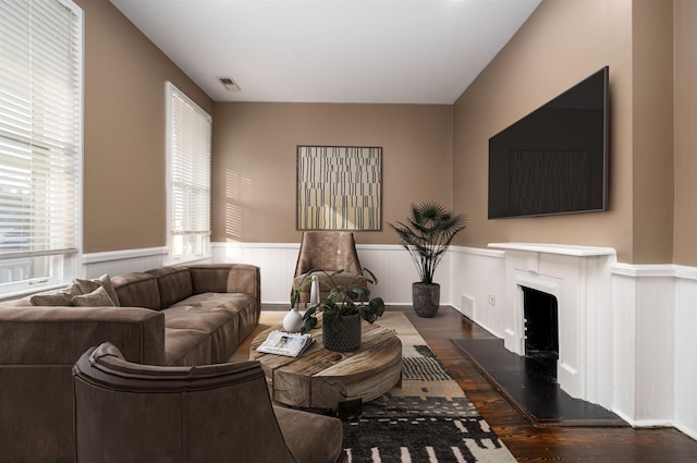 376 Mulberry St, Memphis, TN 38103 - living room featuring a fireplace with raised hearth, visible vents, wood finished floors, and a wainscoted wall