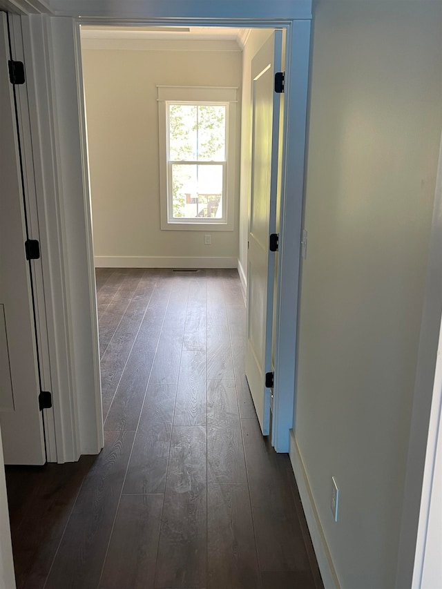 hall featuring ornamental molding, dark wood-style flooring, visible vents, and baseboards