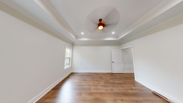 spare room with baseboards, ornamental molding, wood finished floors, a tray ceiling, and recessed lighting