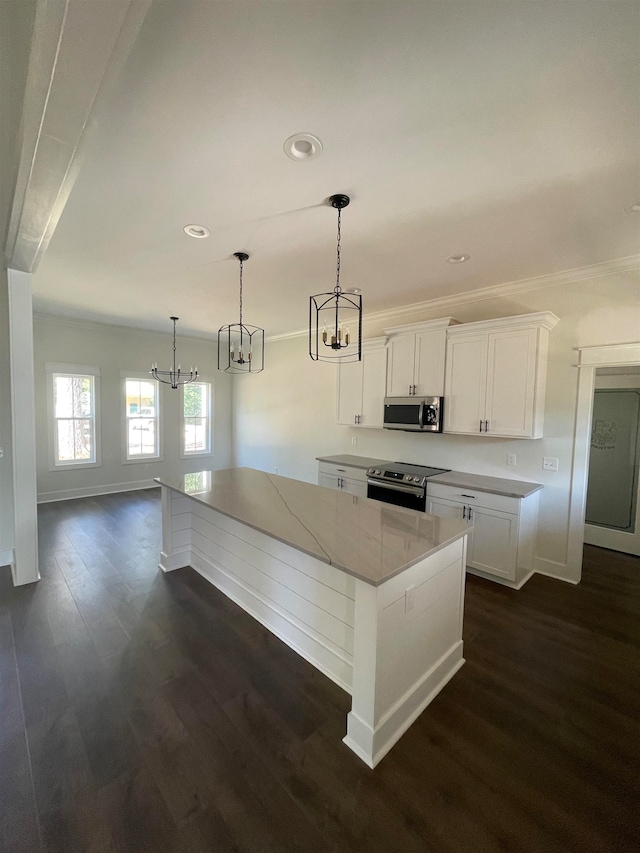 kitchen with dark wood finished floors, a large island, stainless steel appliances, white cabinetry, and baseboards