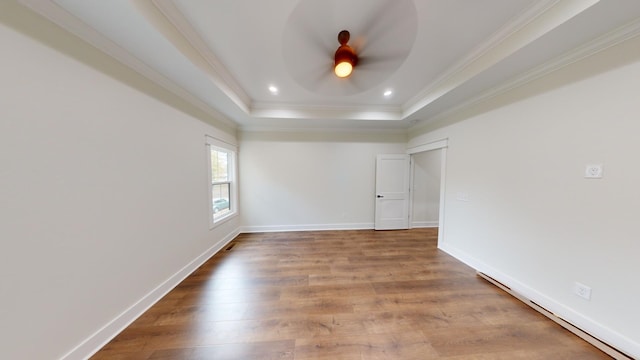 spare room featuring ornamental molding, wood-type flooring, ceiling fan, and a raised ceiling