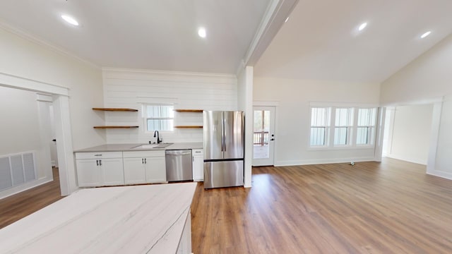 kitchen featuring light wood finished floors, open shelves, visible vents, appliances with stainless steel finishes, and a sink