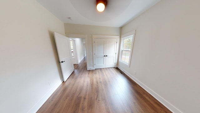 unfurnished bedroom with ceiling fan, a closet, baseboards, and wood finished floors