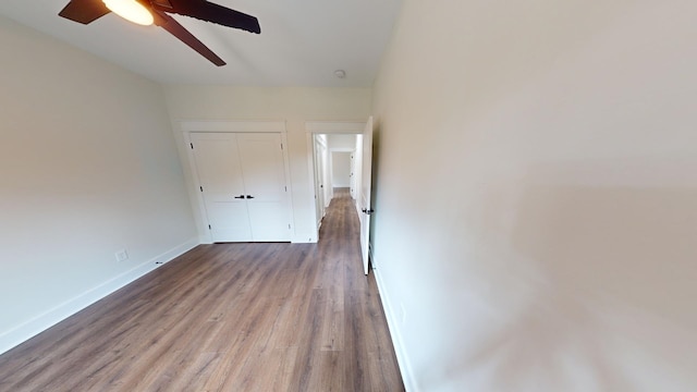 unfurnished bedroom featuring a closet, ceiling fan, baseboards, and wood finished floors