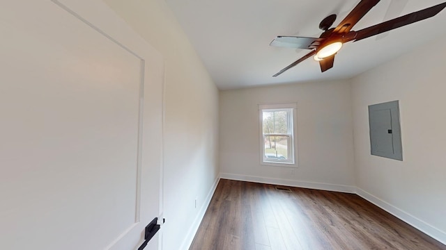 unfurnished room featuring ceiling fan, wood finished floors, electric panel, and baseboards