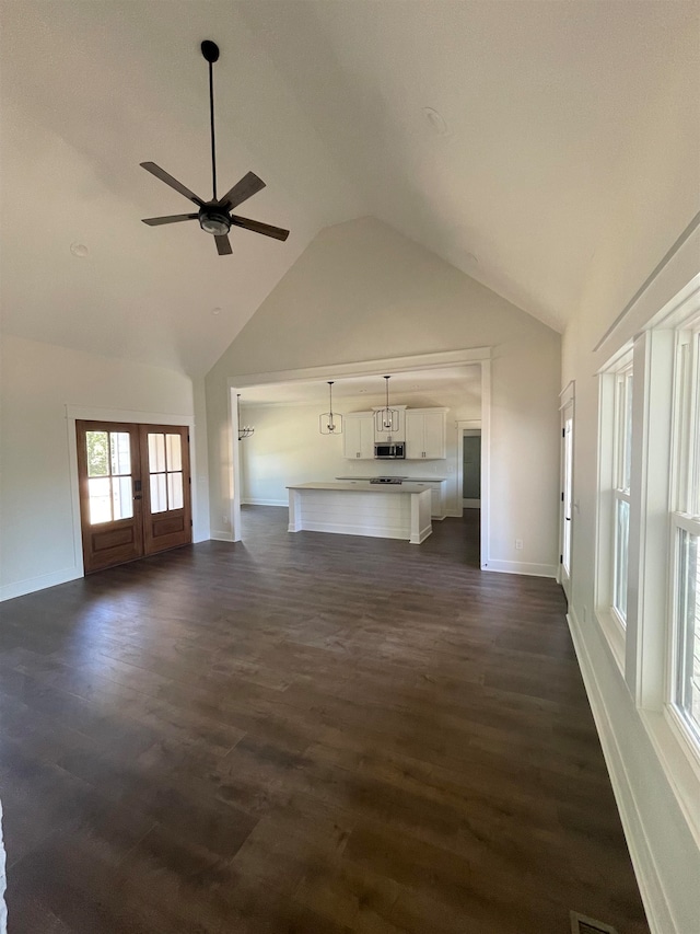 unfurnished living room with french doors, high vaulted ceiling, dark wood-type flooring, and ceiling fan