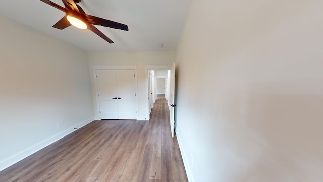 interior space featuring a ceiling fan, a closet, baseboards, and wood finished floors