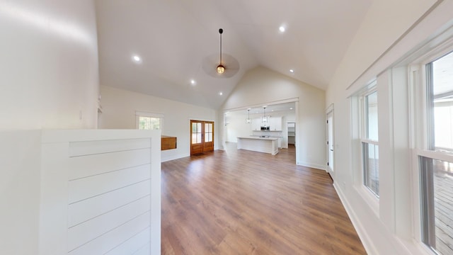 unfurnished living room with high vaulted ceiling, recessed lighting, baseboards, and wood finished floors