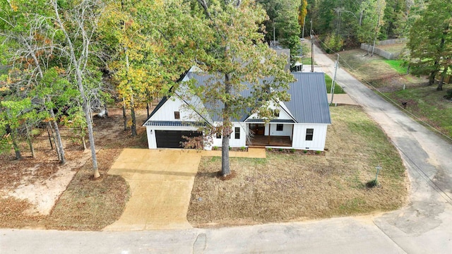 view of front of property featuring a garage, covered porch, metal roof, and driveway