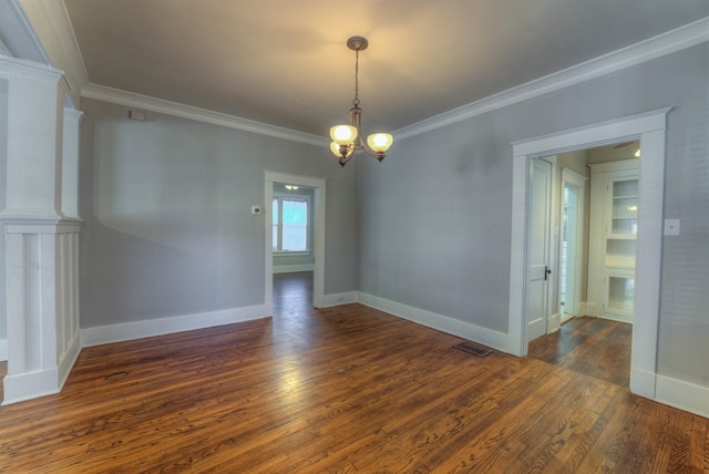 spare room featuring crown molding, ornate columns, dark hardwood / wood-style floors, and a chandelier