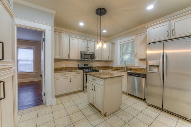 kitchen with sink, light stone countertops, a center island, pendant lighting, and appliances with stainless steel finishes