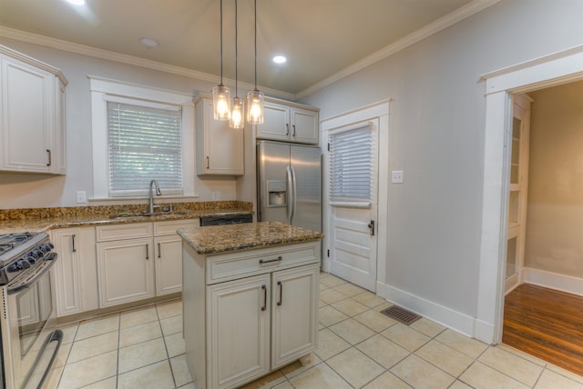 kitchen featuring hanging light fixtures, sink, a center island, light tile patterned flooring, and appliances with stainless steel finishes