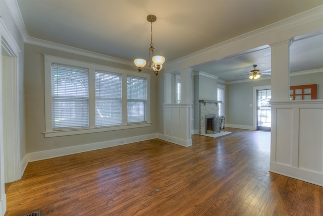 unfurnished living room featuring ornamental molding, a stone fireplace, ceiling fan with notable chandelier, and dark hardwood / wood-style flooring