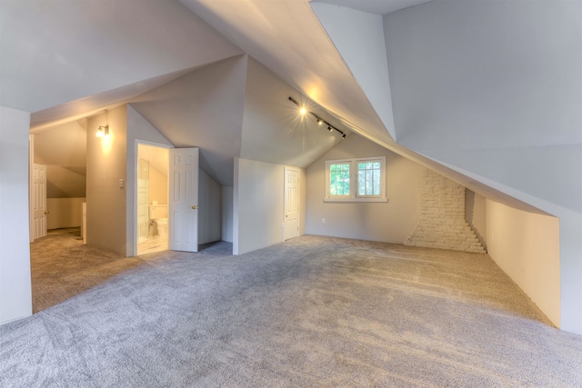 additional living space featuring light carpet and vaulted ceiling