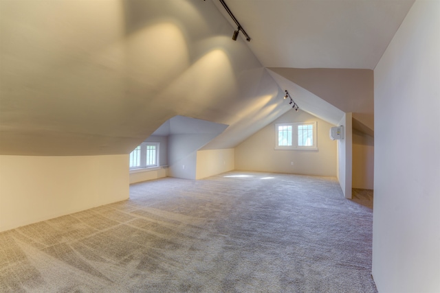 additional living space featuring lofted ceiling, light carpet, and a healthy amount of sunlight