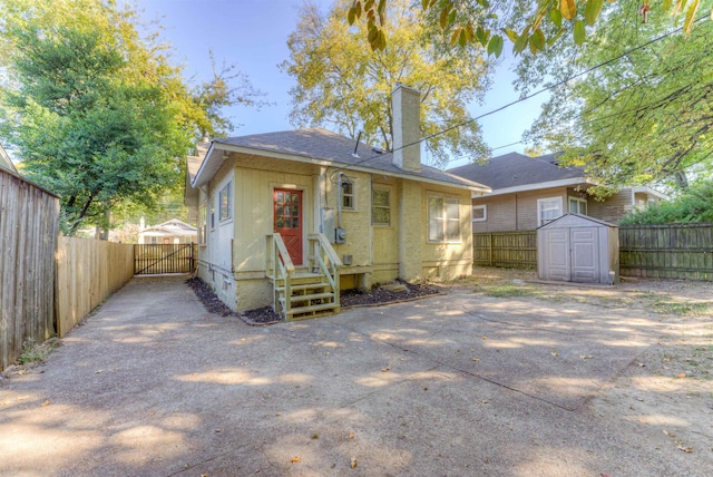 rear view of property with a storage shed