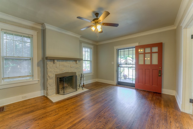 unfurnished living room featuring crown molding, a stone fireplace, dark hardwood / wood-style floors, and ceiling fan