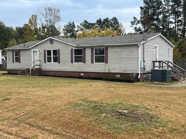 rear view of property with central AC unit and a lawn