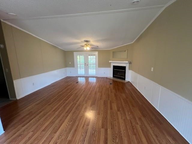 unfurnished living room featuring wood-type flooring, french doors, a textured ceiling, ceiling fan, and ornamental molding