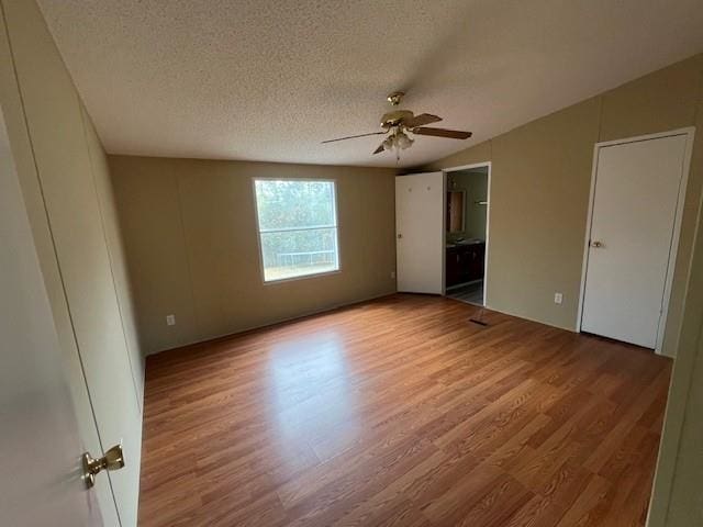 unfurnished bedroom featuring hardwood / wood-style floors, ensuite bath, a textured ceiling, and ceiling fan