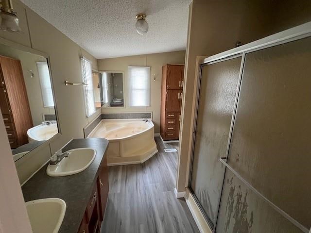 bathroom with independent shower and bath, a textured ceiling, lofted ceiling, vanity, and hardwood / wood-style flooring